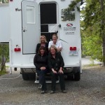 picture of Accent Inns sales team sitting by a camper for their northern trip